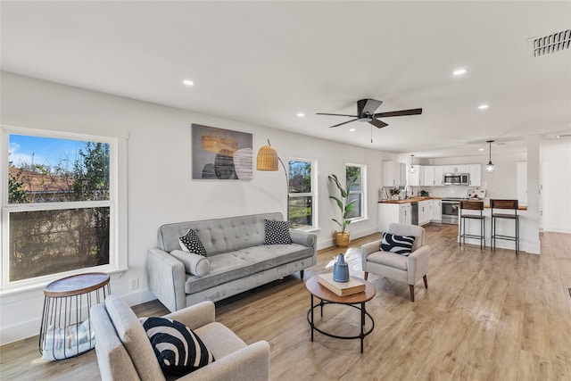 living room with ceiling fan, light hardwood / wood-style floors, and sink