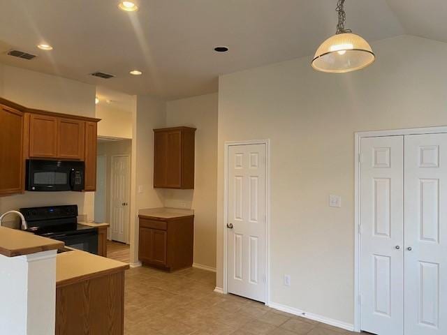 kitchen with hanging light fixtures, vaulted ceiling, and black appliances