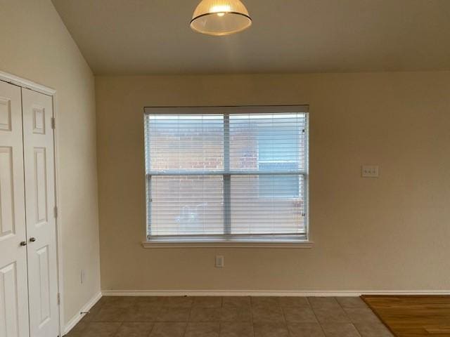 unfurnished room featuring a healthy amount of sunlight and dark tile patterned flooring