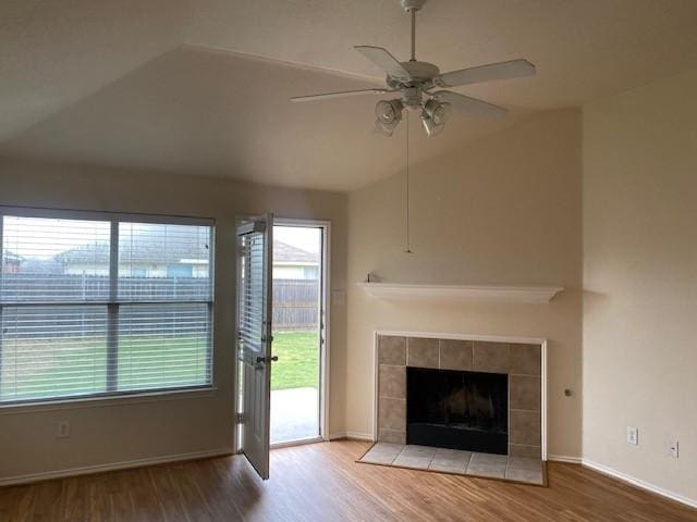 unfurnished living room with hardwood / wood-style flooring, a tile fireplace, lofted ceiling, and ceiling fan