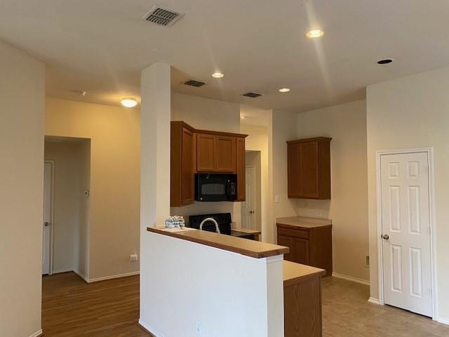 kitchen featuring stove, sink, light wood-type flooring, and kitchen peninsula