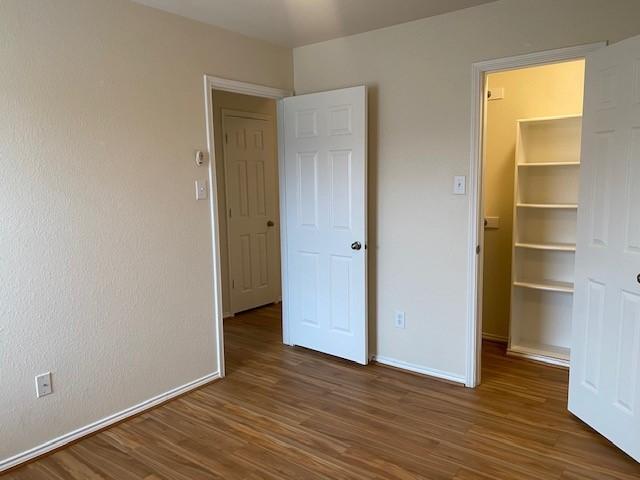 unfurnished bedroom with a closet, dark wood-type flooring, and a spacious closet