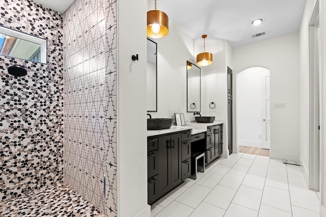 bathroom with tile patterned flooring, vanity, and tiled shower