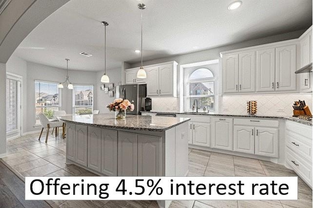 kitchen with a center island, arched walkways, freestanding refrigerator, a sink, and light stone countertops