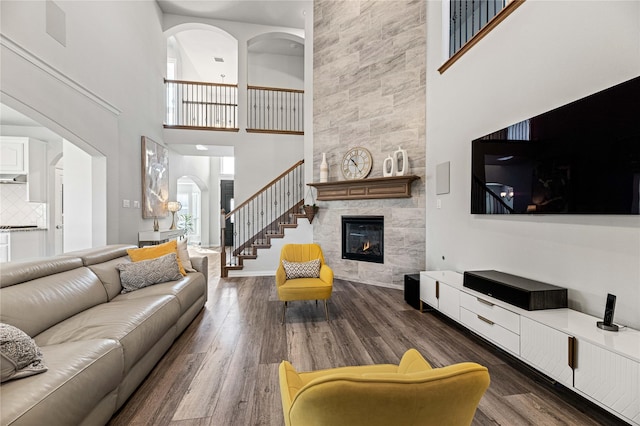 living room featuring a tile fireplace, a high ceiling, and dark hardwood / wood-style flooring