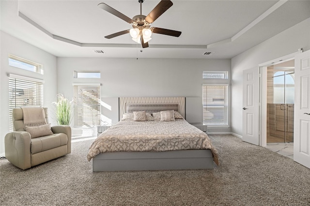 bedroom with a raised ceiling, multiple windows, and ceiling fan