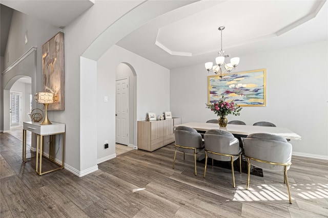 dining area featuring a tray ceiling, dark hardwood / wood-style flooring, and an inviting chandelier