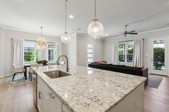 kitchen featuring sink, white cabinets, hanging light fixtures, and a center island with sink