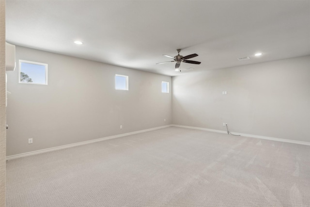 basement featuring light carpet, plenty of natural light, and ceiling fan