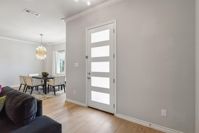 foyer entrance featuring a notable chandelier, light wood-type flooring, and crown molding