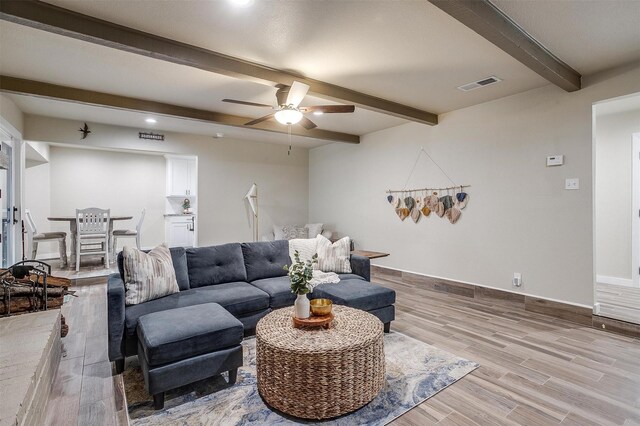 living room featuring beam ceiling, ceiling fan, and light hardwood / wood-style flooring