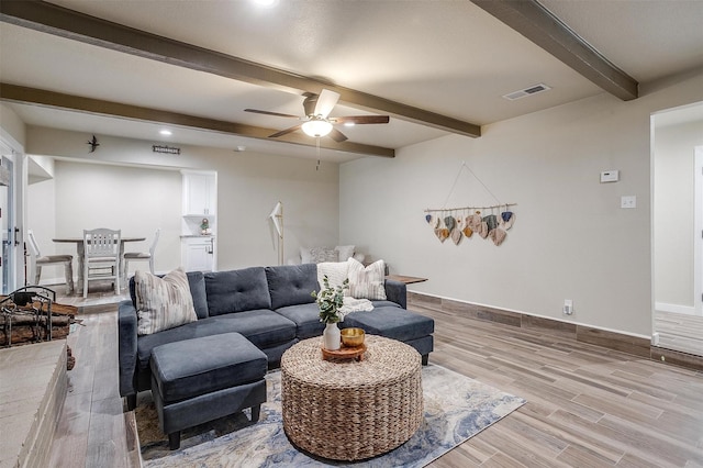 living room with ceiling fan, beam ceiling, and light hardwood / wood-style flooring