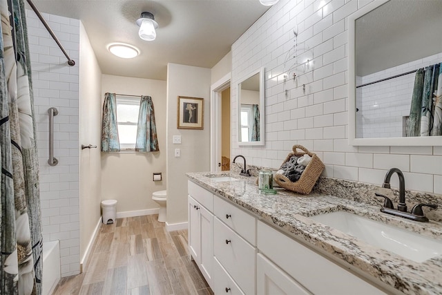 full bathroom featuring hardwood / wood-style floors, vanity, tiled shower / bath, toilet, and tasteful backsplash