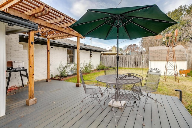 deck with a storage unit, a yard, and a pergola