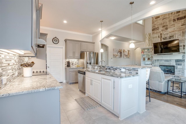 kitchen featuring appliances with stainless steel finishes, pendant lighting, an island with sink, sink, and gray cabinetry