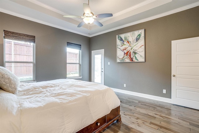 bedroom with a raised ceiling, wood-type flooring, ceiling fan, and crown molding