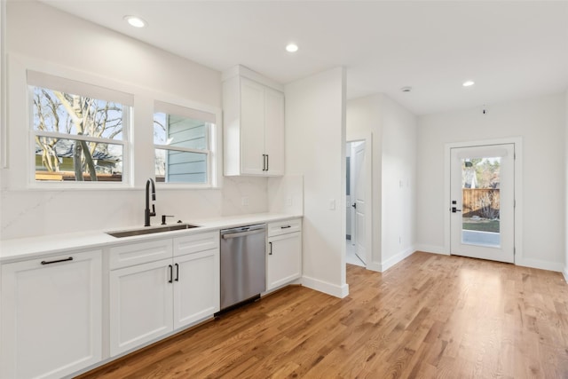 kitchen featuring sink, tasteful backsplash, stainless steel dishwasher, light hardwood / wood-style floors, and white cabinets