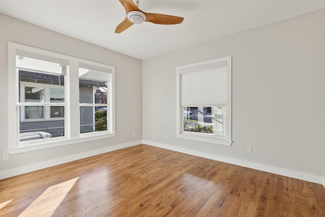 empty room featuring plenty of natural light, ceiling fan, and wood-type flooring