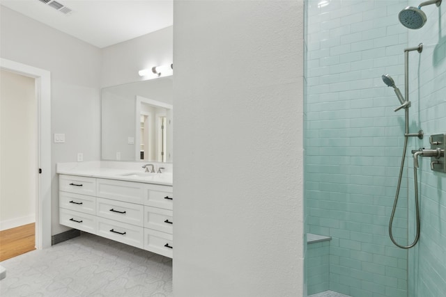 bathroom with tile patterned flooring, vanity, and tiled shower