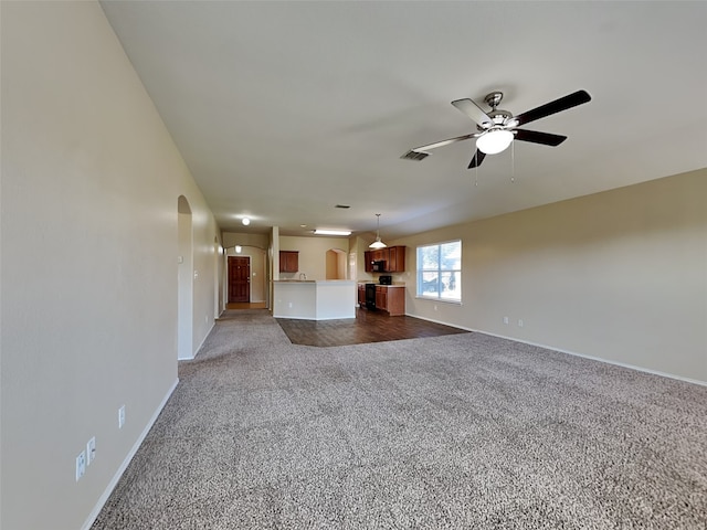 unfurnished living room with dark colored carpet and ceiling fan