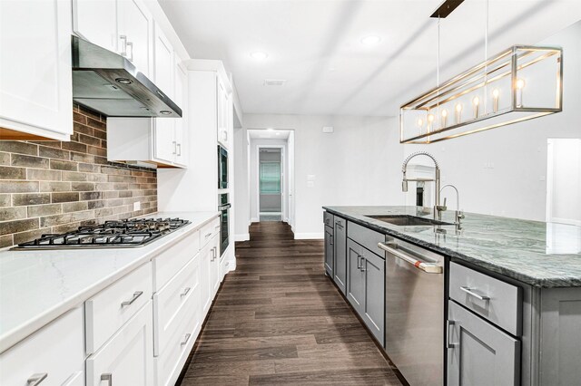 kitchen featuring sink, range hood, dark stone counters, white cabinets, and appliances with stainless steel finishes