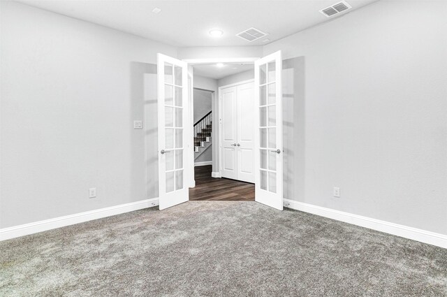 unfurnished room featuring french doors and dark carpet