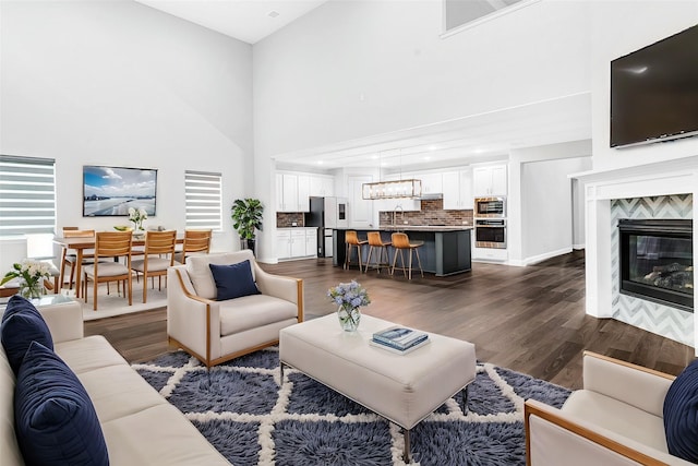 living room featuring a high ceiling, sink, dark hardwood / wood-style flooring, and a tiled fireplace