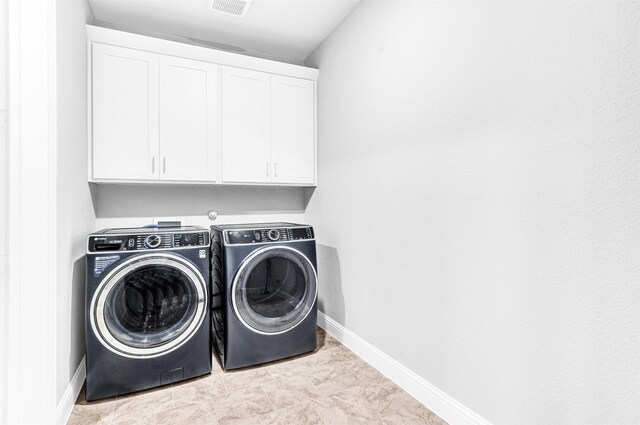 clothes washing area with cabinets and independent washer and dryer