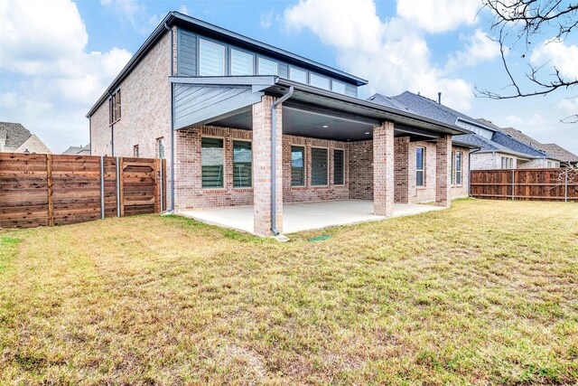 back of property with a yard and a patio