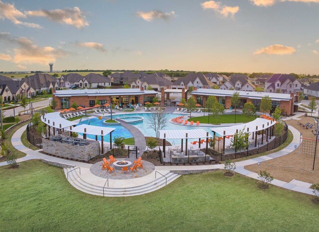 pool at dusk featuring a fire pit and a lawn