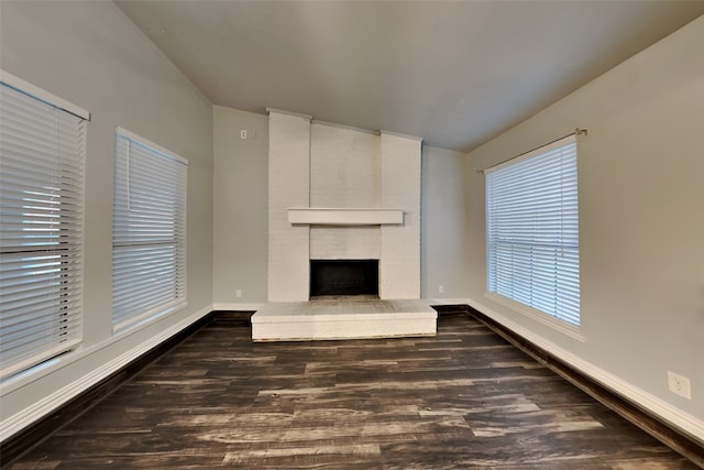 unfurnished living room featuring a brick fireplace and dark hardwood / wood-style flooring