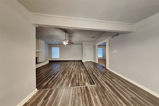 unfurnished living room featuring ceiling fan, a fireplace, lofted ceiling with beams, and hardwood / wood-style floors