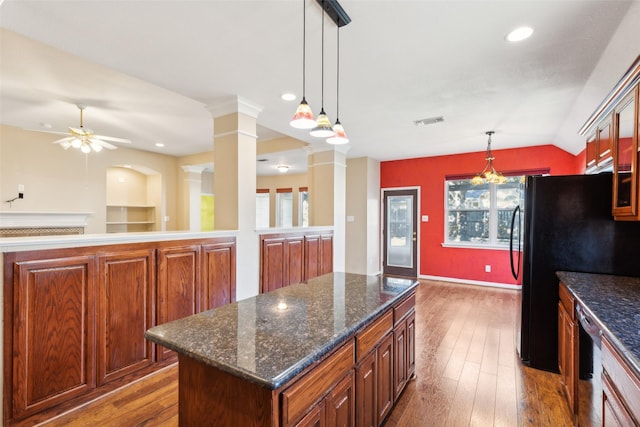 kitchen featuring hardwood / wood-style flooring, decorative columns, a kitchen island, decorative light fixtures, and vaulted ceiling