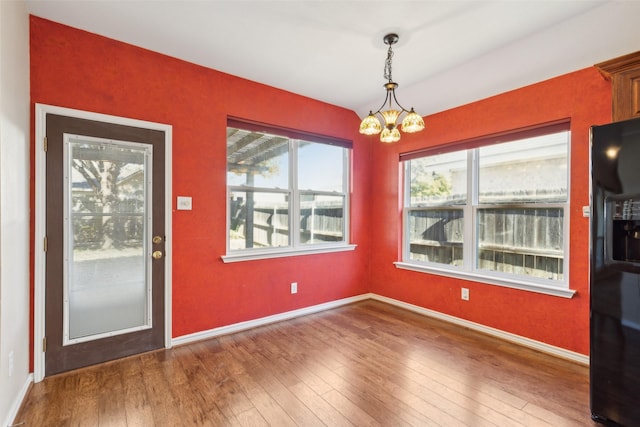 unfurnished dining area with an inviting chandelier and hardwood / wood-style floors