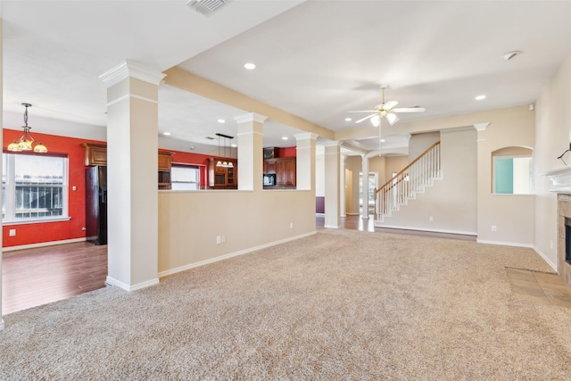 unfurnished living room with ornate columns, a tile fireplace, carpet floors, and ceiling fan