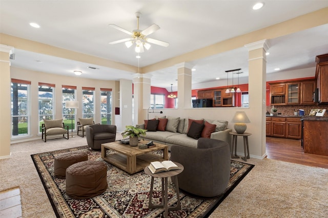 living room with dark colored carpet, ceiling fan, and ornate columns