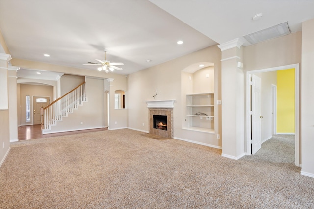 unfurnished living room featuring ceiling fan, light colored carpet, a fireplace, and built in features