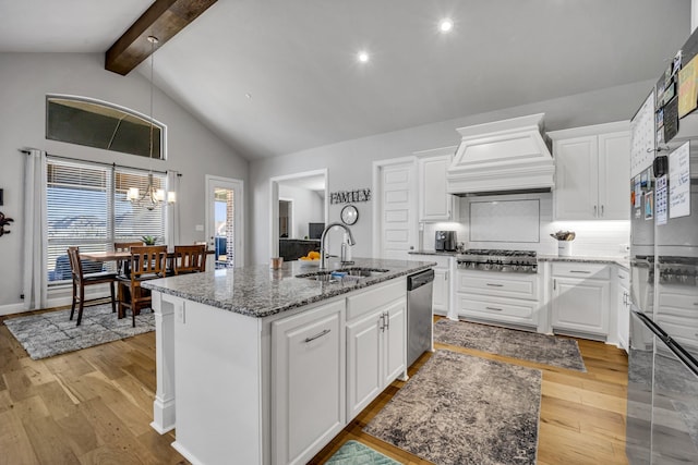 kitchen with custom range hood, stainless steel appliances, sink, a center island with sink, and white cabinets