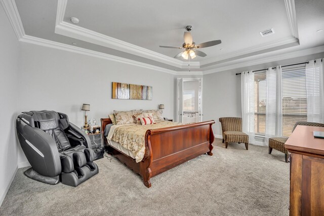 carpeted bedroom with a tray ceiling, ceiling fan, and crown molding