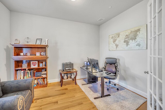 home office with hardwood / wood-style flooring and french doors