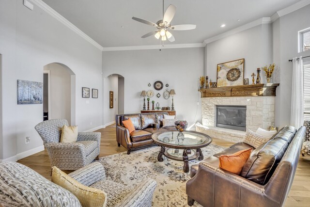 living room featuring crown molding, a fireplace, ceiling fan, and light hardwood / wood-style floors