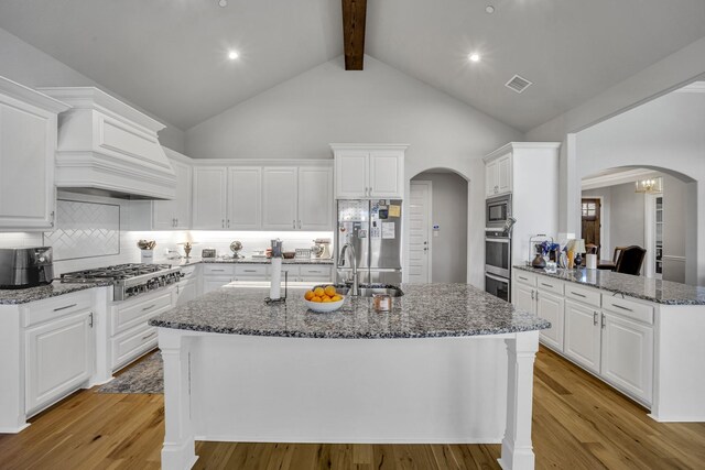 kitchen with white cabinets, stainless steel appliances, high vaulted ceiling, and tasteful backsplash