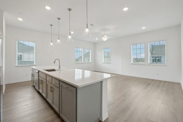 2402 Bulin Dr, Mansfield, TX 76063 - kitchen with light wood finished floors, ceiling fan, a center island with sink, a sink, and gray cabinets