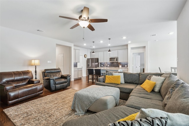 living room featuring ceiling fan, dark hardwood / wood-style flooring, and sink