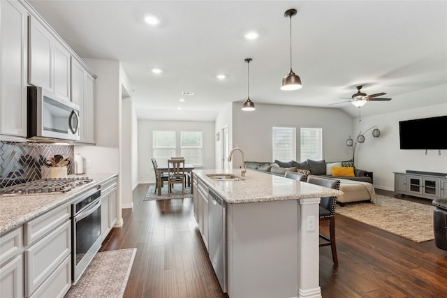 kitchen featuring sink, hanging light fixtures, a kitchen island with sink, white cabinets, and appliances with stainless steel finishes