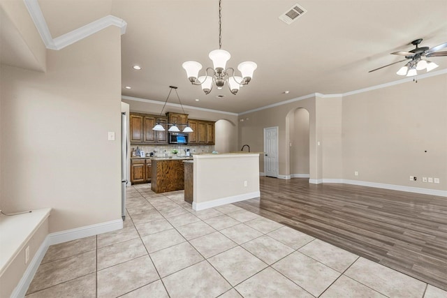 kitchen with ceiling fan with notable chandelier, pendant lighting, tasteful backsplash, a center island, and stainless steel appliances