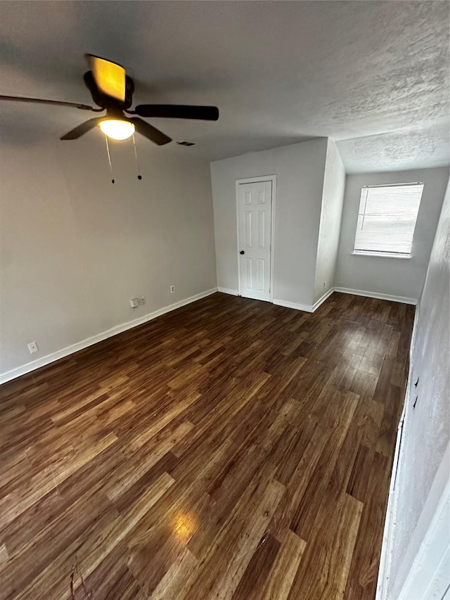 bonus room featuring a textured ceiling, ceiling fan, and dark wood-type flooring