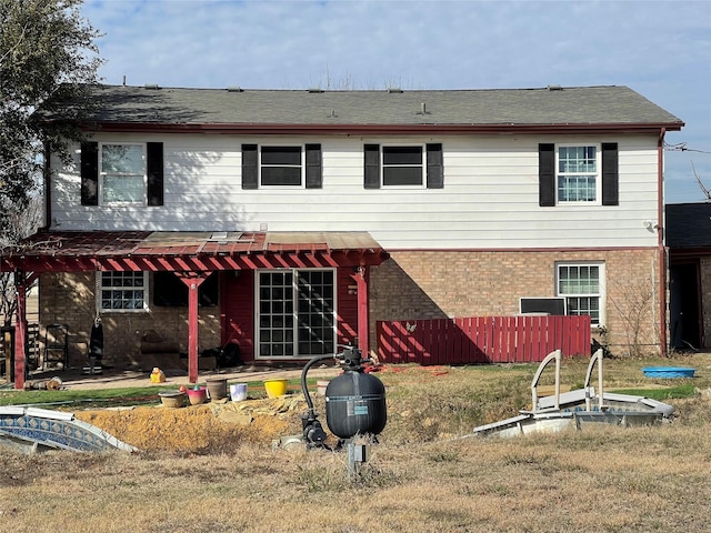 rear view of property featuring fence and brick siding
