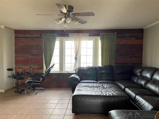 living area featuring light tile patterned floors, wooden walls, a ceiling fan, crown molding, and a textured ceiling