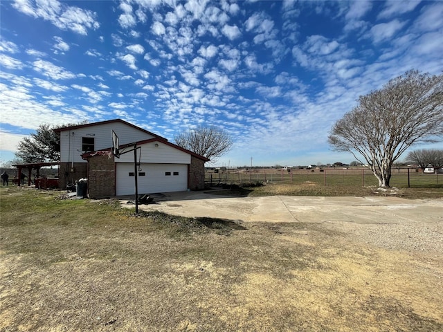 view of yard with an attached garage, fence, concrete driveway, and an outbuilding